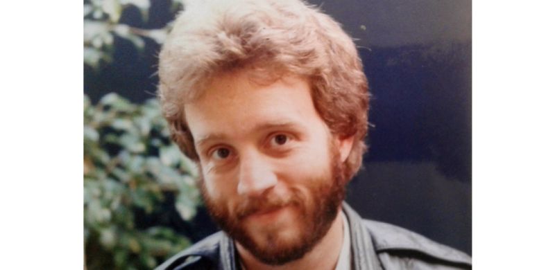 Dale with a beard and puffy hair smiling
