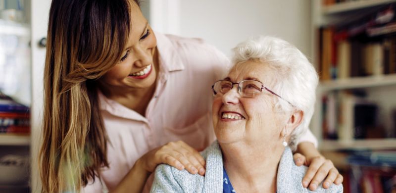 Younger woman smiling and warmly embracing an older woman.