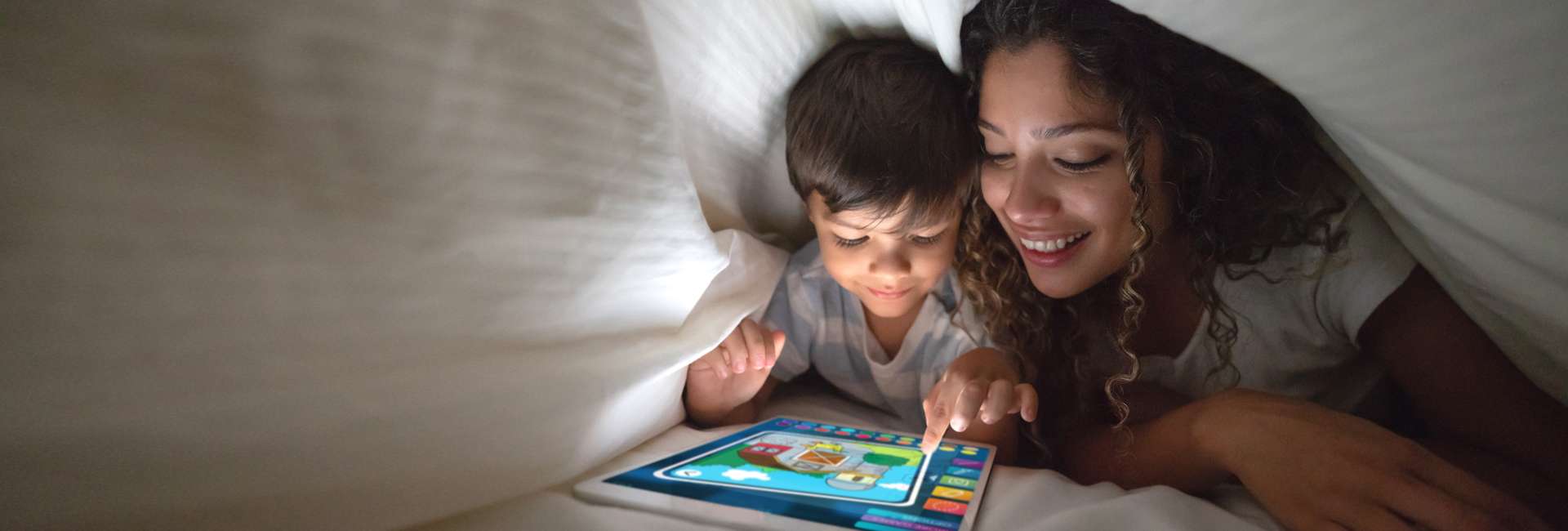woman and her son on an ipad under the sheets
